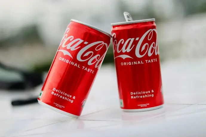 two cans of coca cola sitting on a table